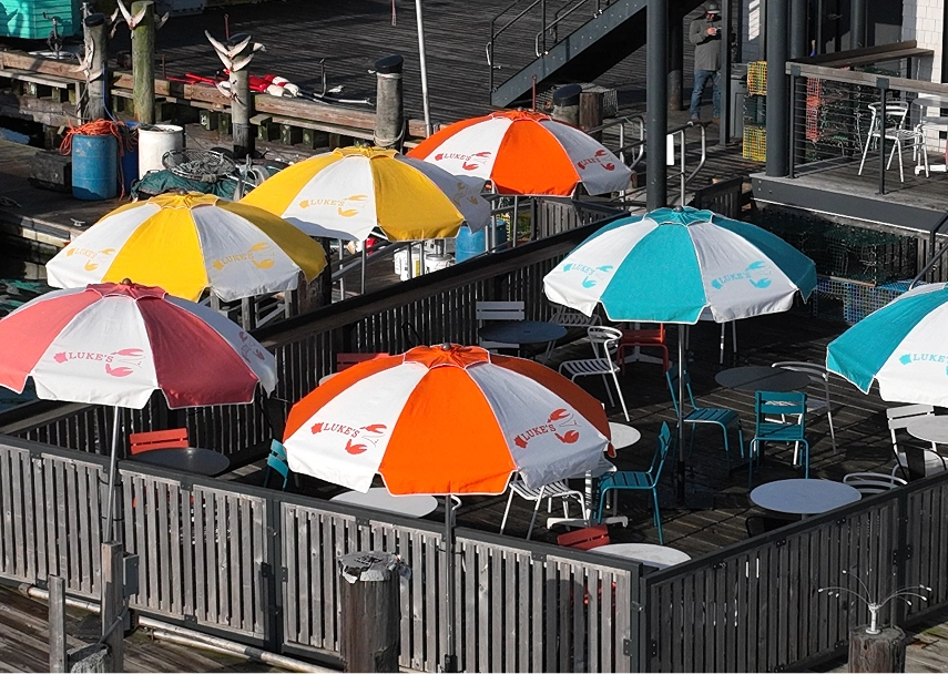 Outdoor dining area at Luke's Lobster with multicolor branded umbrellas covering guest seating.
