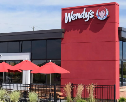 Wendy's restaurant patio featuring bright red market umbrellas shading outdoor dining tables.