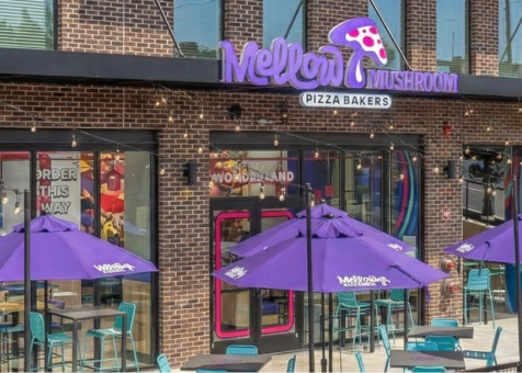 Outdoor seating area at Mellow Mushroom featuring custom purple branded umbrellas over patio tables.