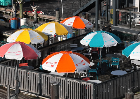 Outdoor dining area at Luke's Lobster with multicolor branded umbrellas covering guest seating.