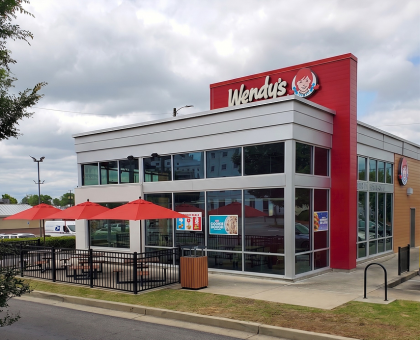 Wendy's restaurant patio featuring bright red market umbrellas shading outdoor dining tables.