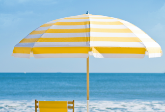 Yellow and white striped beach umbrella with matching chair overlooking a bright blue ocean