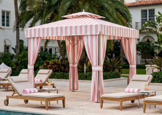 Pink and white Marbella cabana structure beside a resort pool with lounge seating in a sunny setting