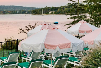 Pink and white fringe umbrellas at the Claremont Hotel overlooking a harbor at sunset.