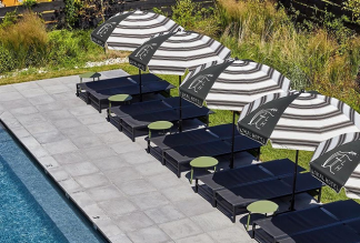Row of black and white custom logo umbrellas lining a resort pool deck.