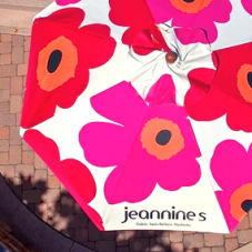 Custom full-print market umbrella for Jeannine's featuring vibrant pink, red, and orange florals