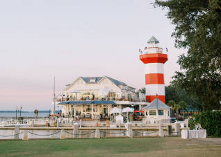 Sunset view of Sea Pines Resort with white cabana umbrellas visible in the distance.
